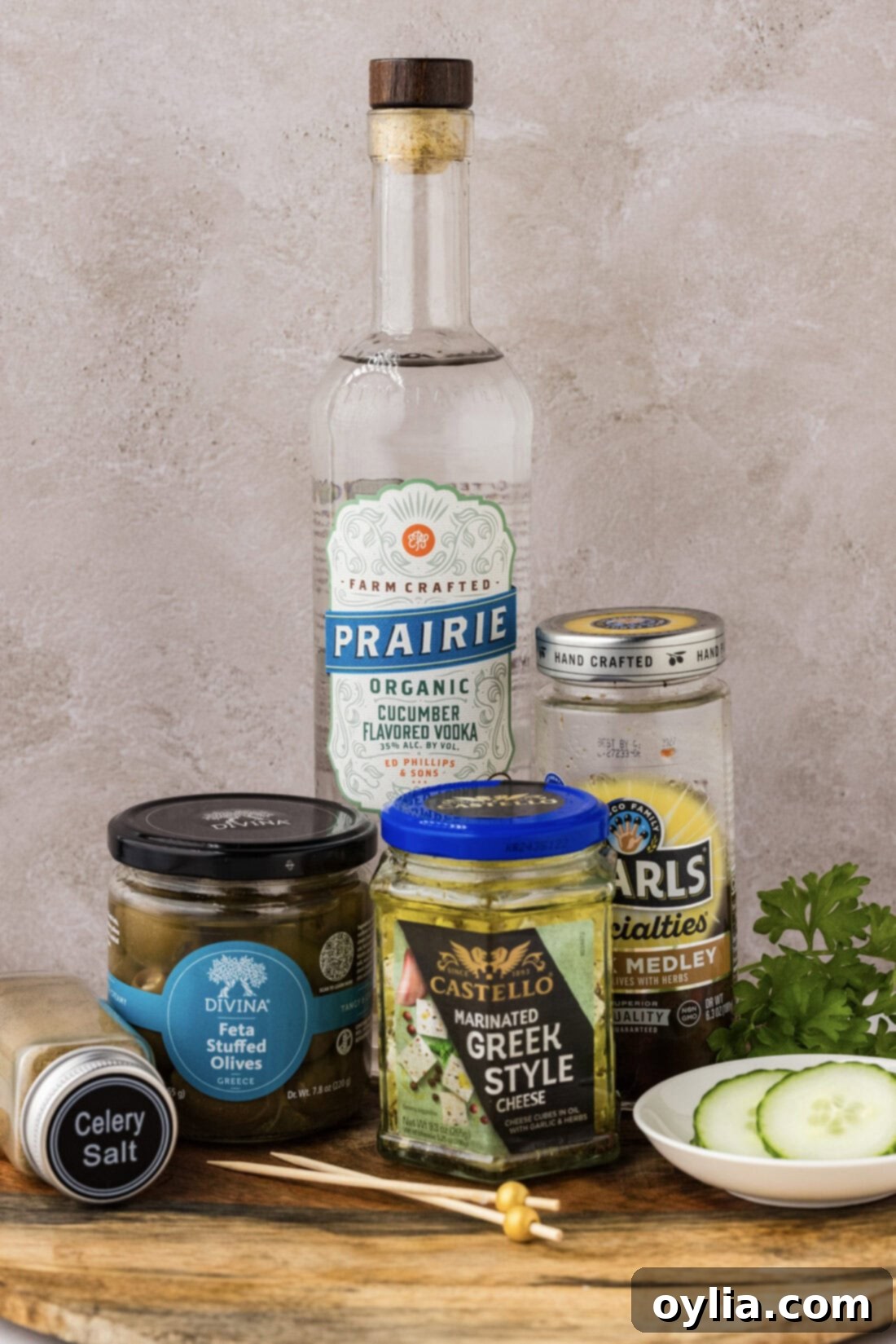 Ingredients for Dirty Greek Martini including cucumber vodka, olive juice, olives, lemon, and celery salt.