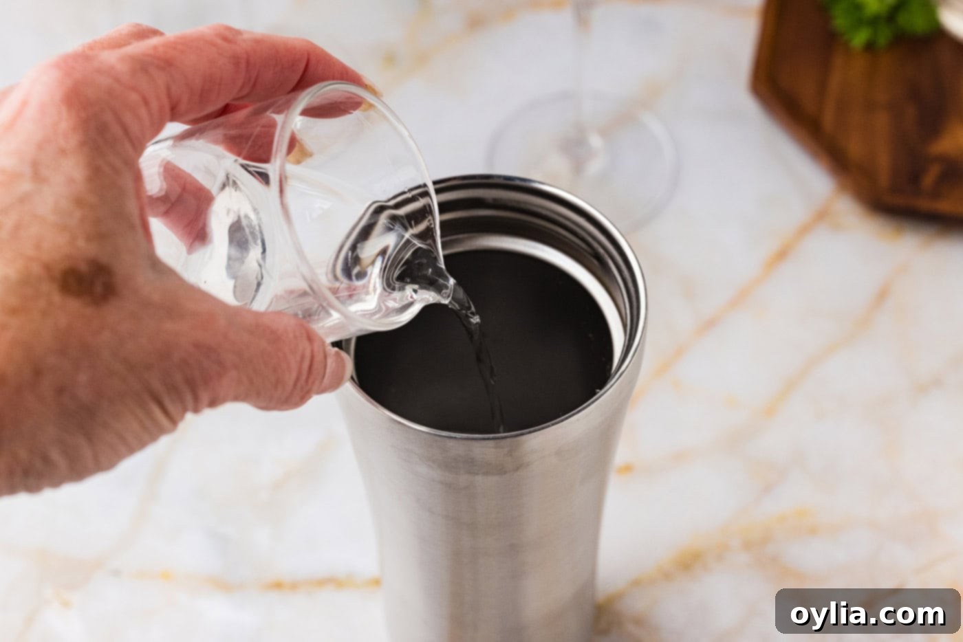 pouring cucumber vodka into a cocktail shaker