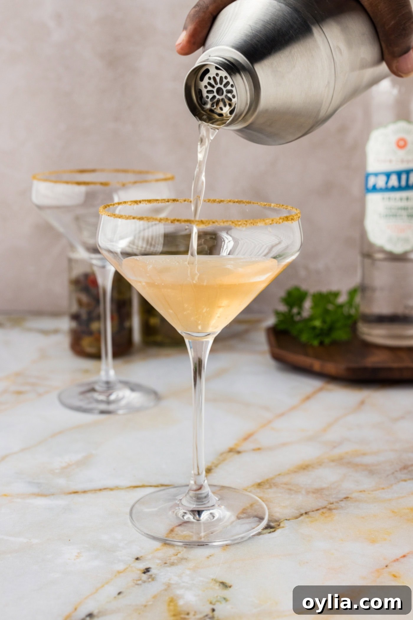 pouring dirty greek martini from a cocktail shaker into a glass