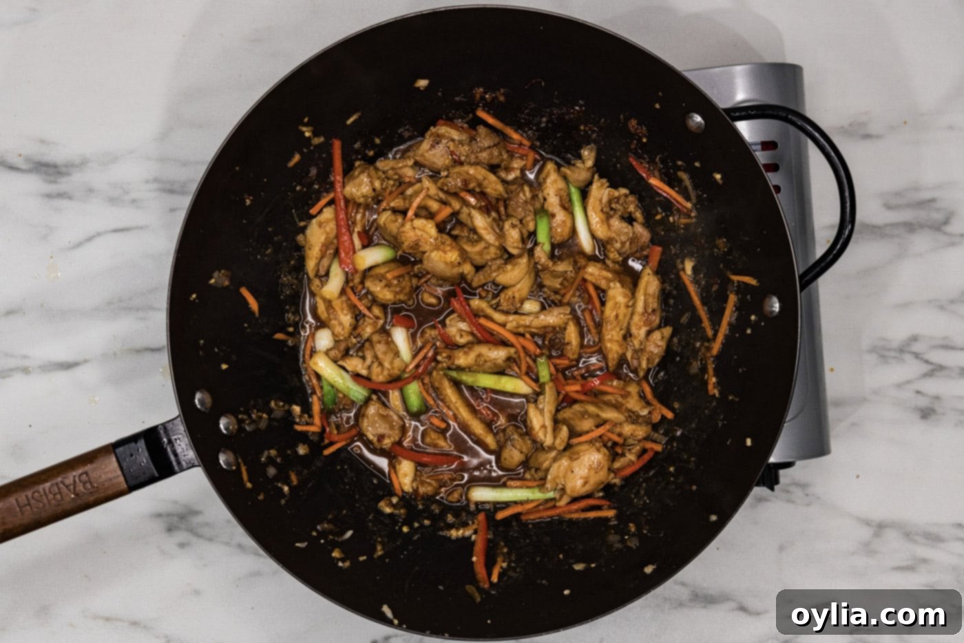 Overhead shot of perfectly cooked Szechuan chicken stir-fry in a wok, rich in color and sauce.