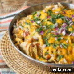 Loaded Rotisserie Chicken Nachos 7 A bowl of loaded rotisserie chicken nachos resting on a wicker place mat.