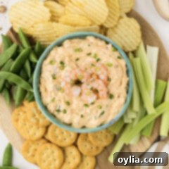 Close up photo of a bowl of Shrimp Dip surrounded by chips and veggies, showcasing its appeal as a party appetizer