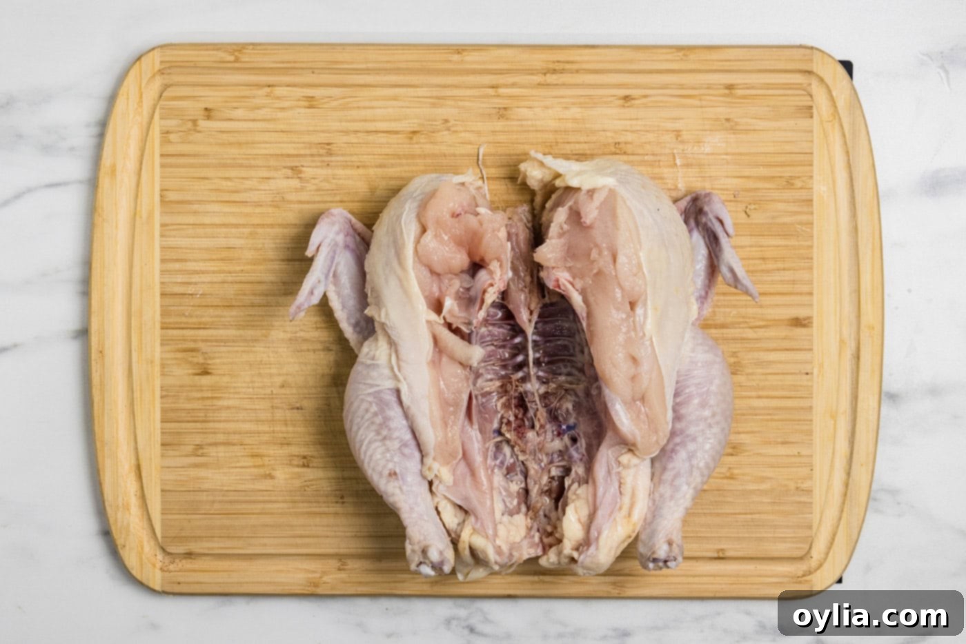 The spatchcocked chicken laying flat on a cutting board, ready for seasoning.