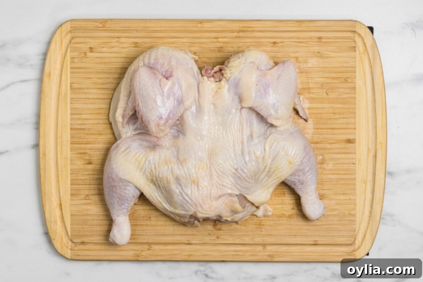 Photo of a flattened, spatchcocked chicken on a cutting board, ready for seasoning.