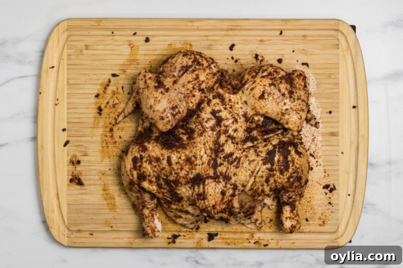 Spices and seasonings being rubbed meticulously onto the spatchcock chicken for maximum flavor.