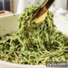 Close up photo of tongs holding up Spinach Spaghetti