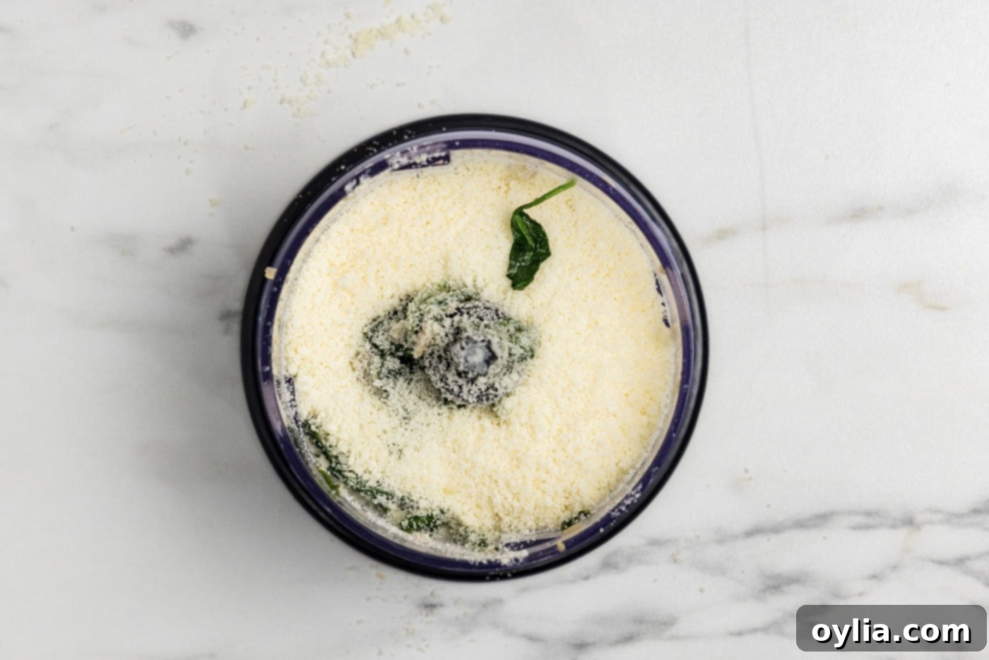 parmesan cheese added to spinach mixture in a food chopper