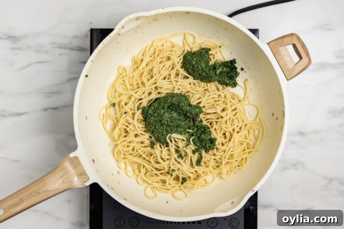 spinach sauce added to skillet with cooked spaghetti noodles