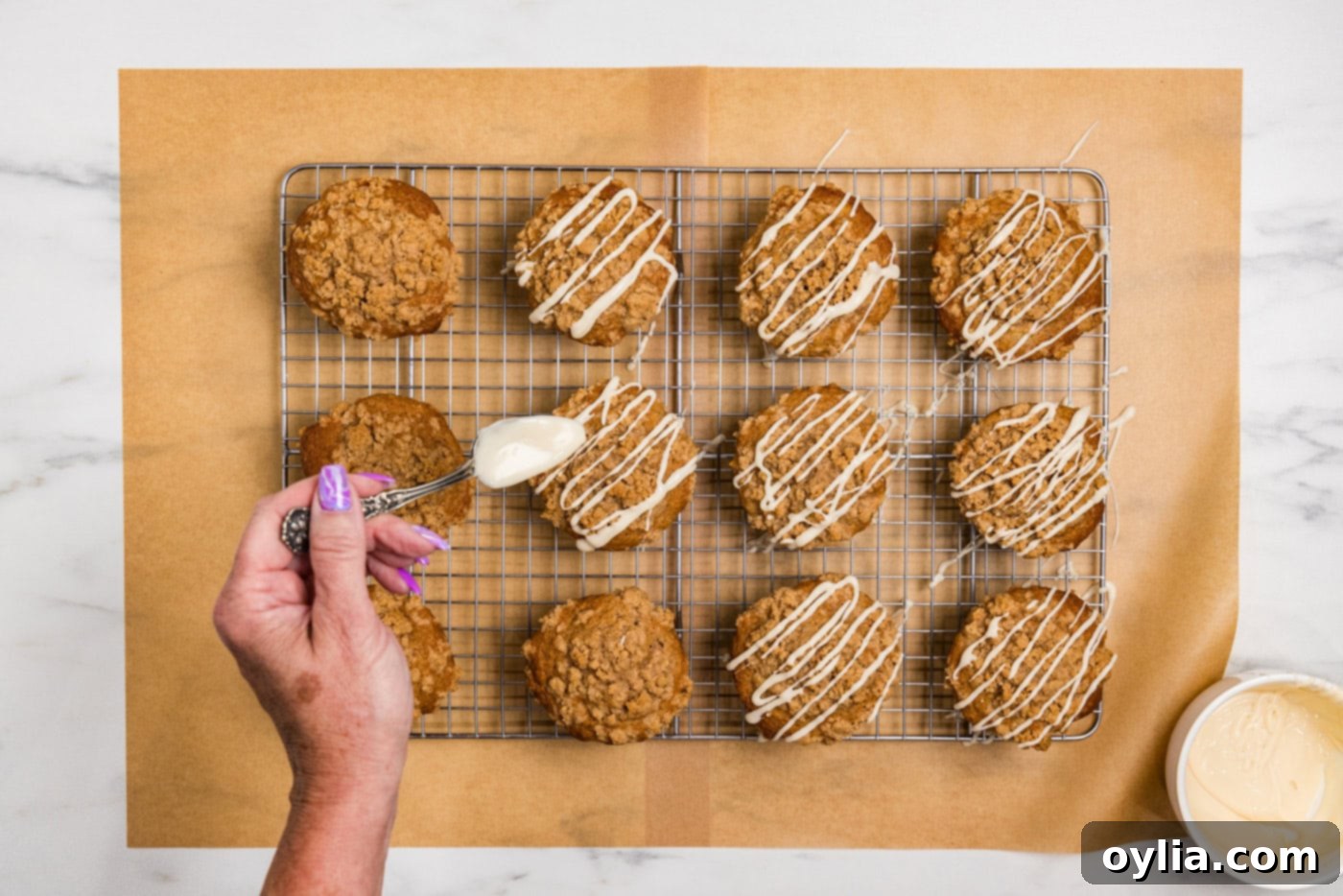 hand drizzling glaze on top of apple streusel muffins