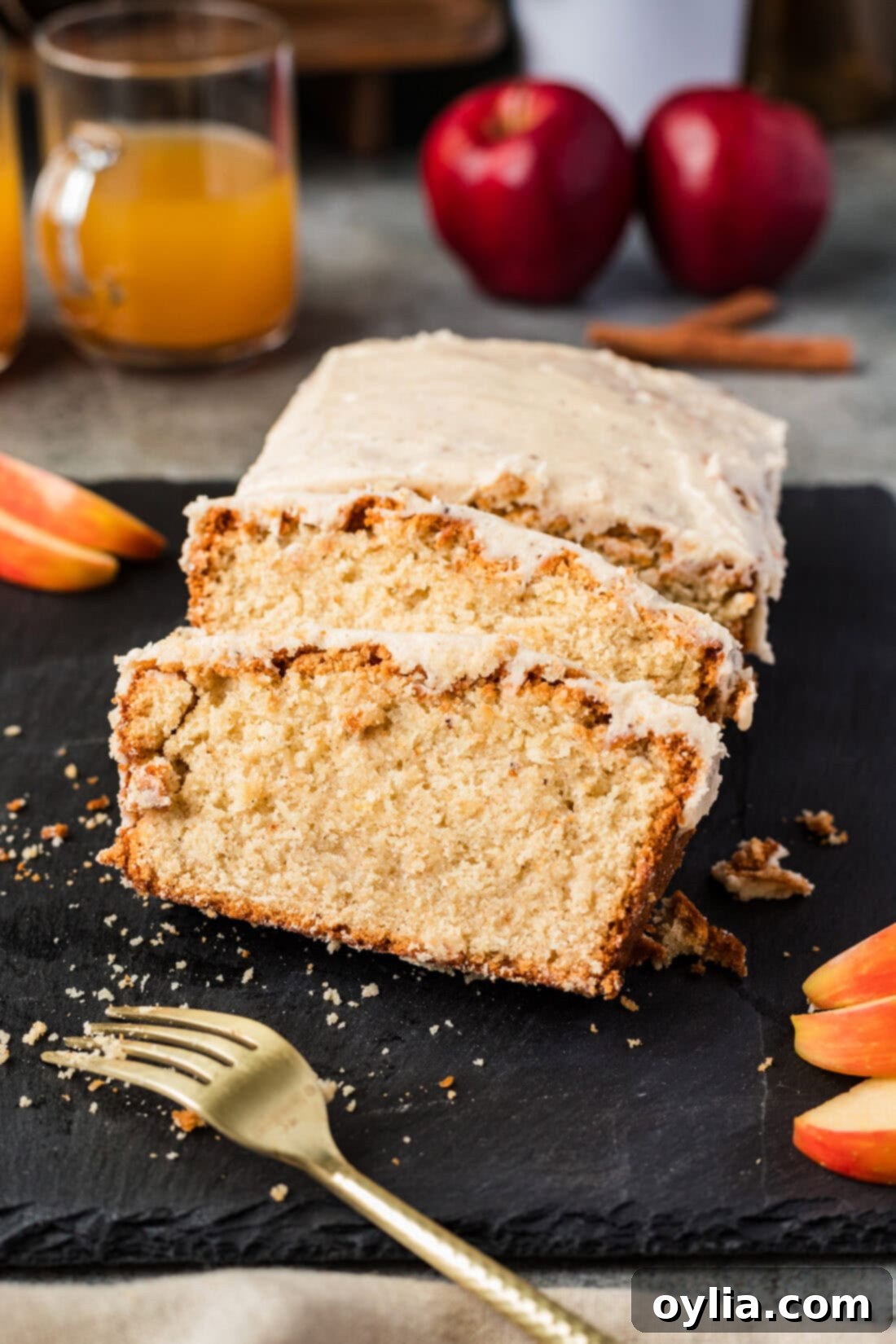 Two slices of Apple Cider Pound Cake resting on the loaf with a fork in front