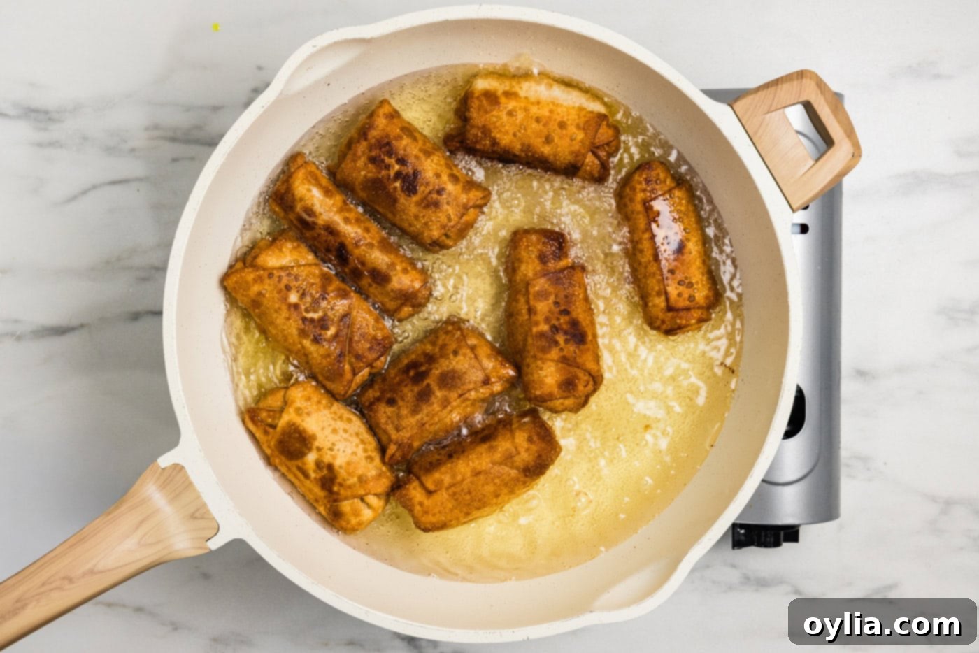 Golden-brown fried buffalo chicken egg rolls sizzling in hot oil
