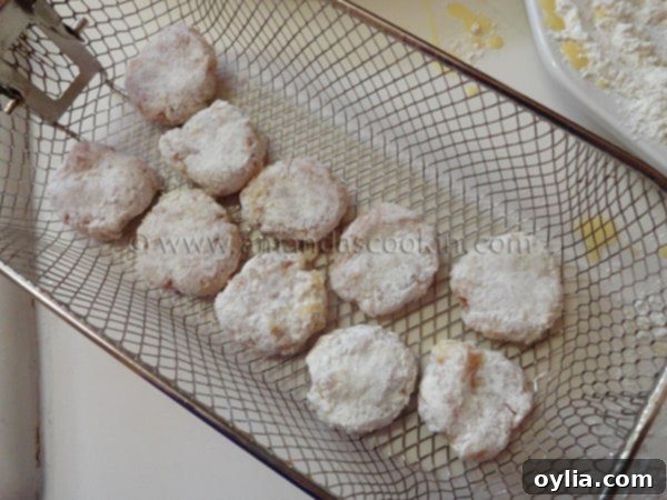 Several raw, breaded chicken nuggets carefully placed in a deep fryer basket, ready to be lowered into hot oil.