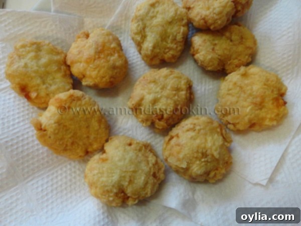 An overhead shot of freshly fried, golden-brown homemade chicken nuggets draining on a paper towel-lined plate.