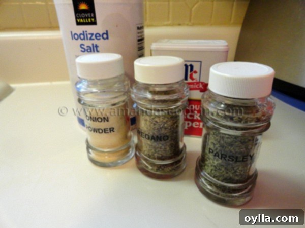 Close-up photo of glass jars containing onion powder, dried oregano, and dried parsley flakes, ready to be combined.
