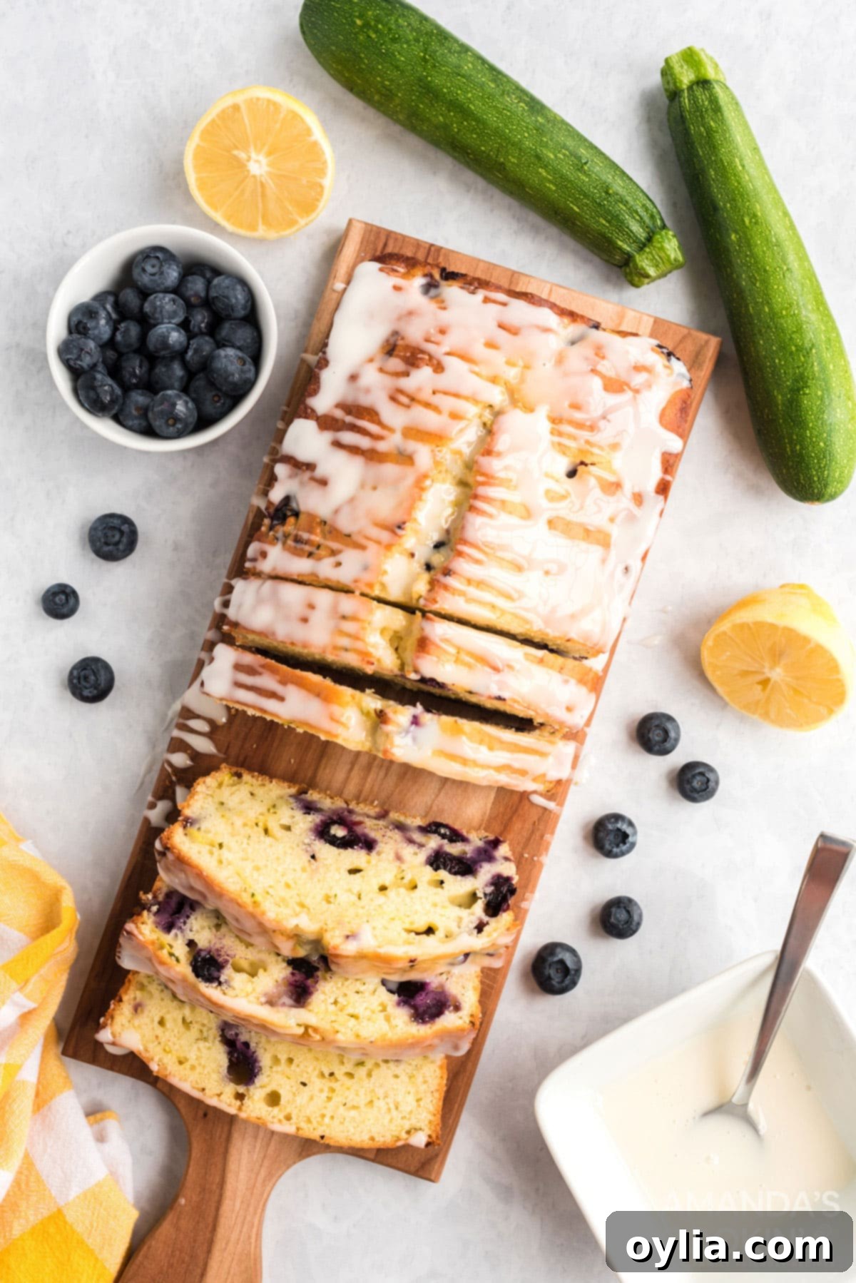 Overhead shot of freshly sliced Lemon Blueberry Zucchini Bread on a wooden cutting board, showcasing the moist interior and vibrant blueberries.