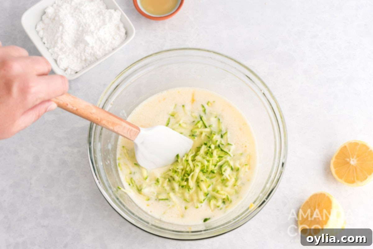 Shredded zucchini being folded into the bread batter.