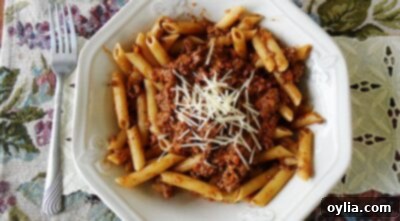 An overhead photo of penne Bolognese with grated parmesan cheese on top.
