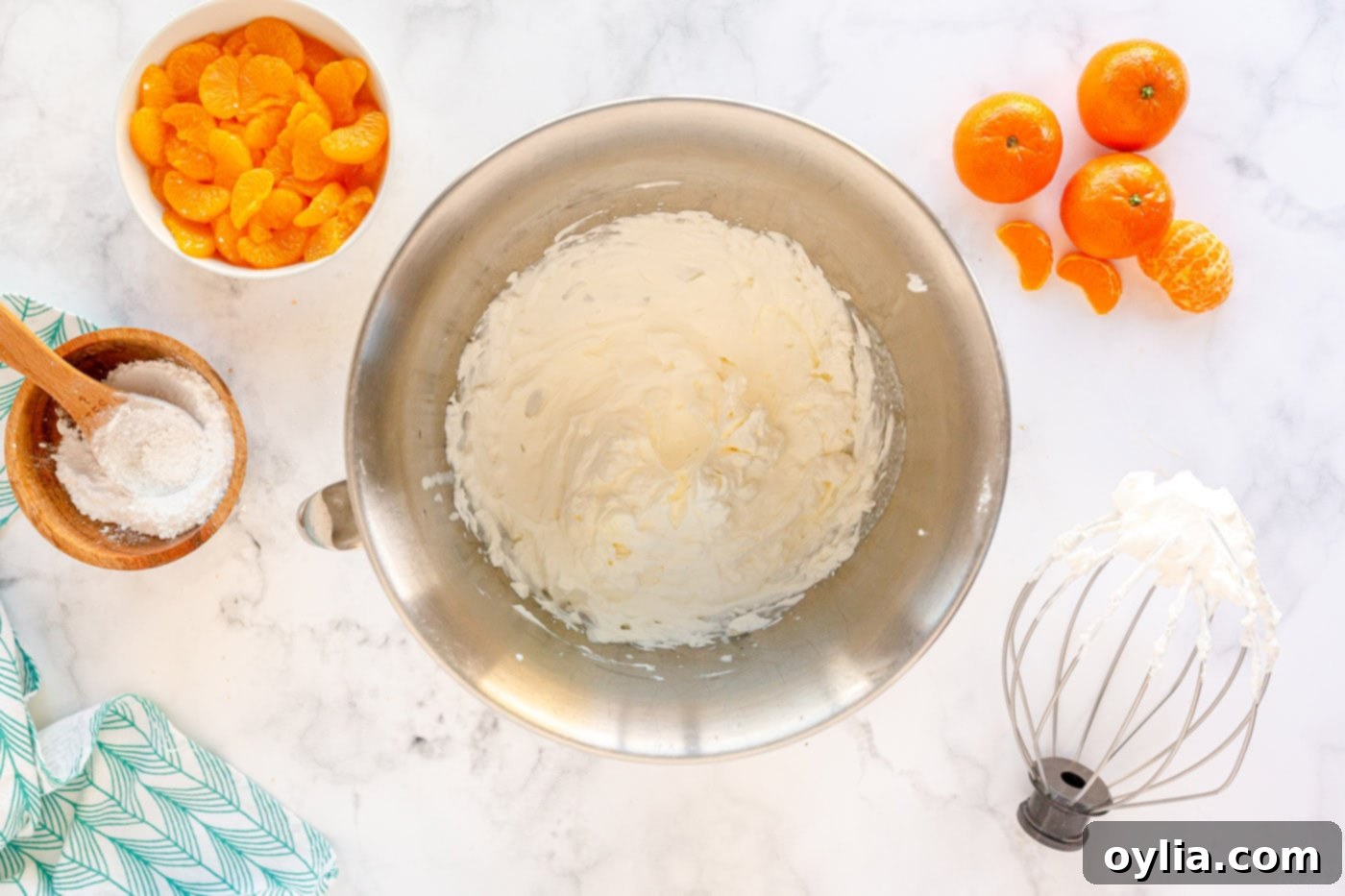 A mixing bowl with cold whipping cream and powdered sugar, ready to be beaten into stiff peaks for the mousse filling.
