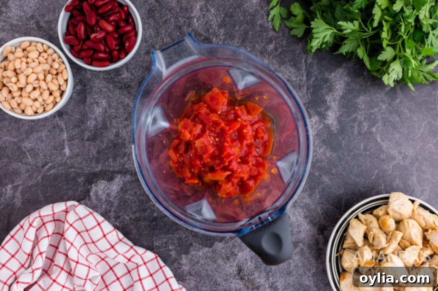 Pureeing canned tomatoes in a food processor for a smooth soup base
