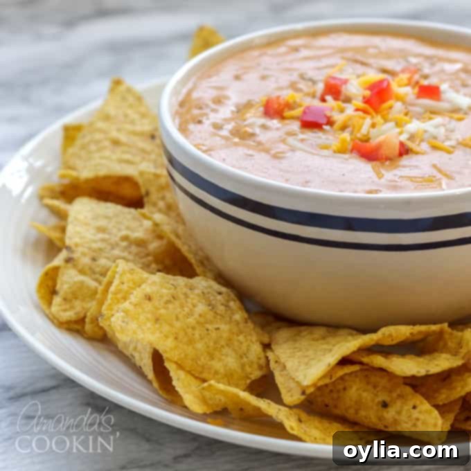 Close-up of a bubbling hot chili cheese dip, ready to be served with tortilla chips.