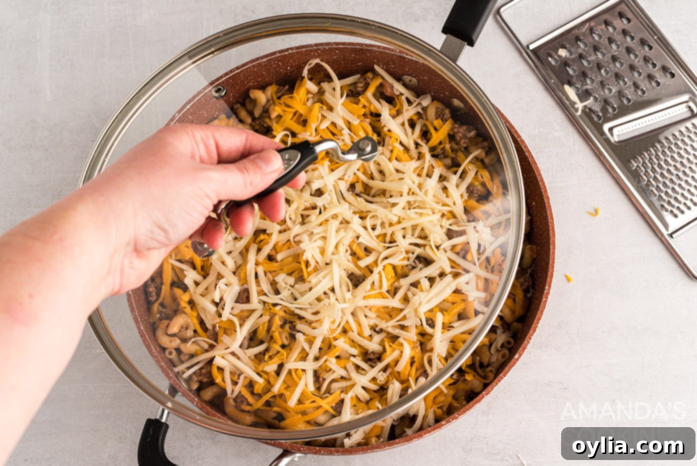 The skillet mixture covered with shredded cheddar and mozzarella cheese, before melting
