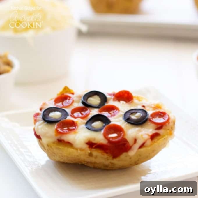 A close up of a baked potato pizza on a white plate topped with pepperoni and black olives.