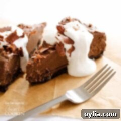 Velvety Avocado Chocolate Mousse Cake 7 A close up of a slice of avocado chocolate mousse cake on a wooden cutting board with a fork next to it.