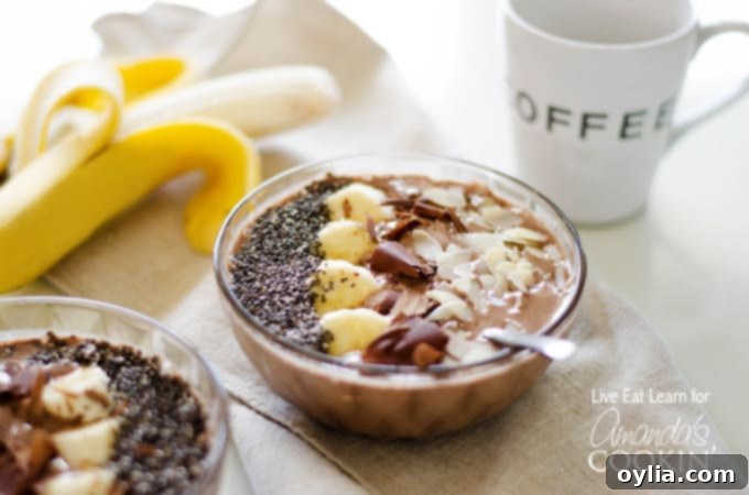 A close up of a mocha smoothie bowl topped with sliced banana, shaved chocolate and sliced almonds.