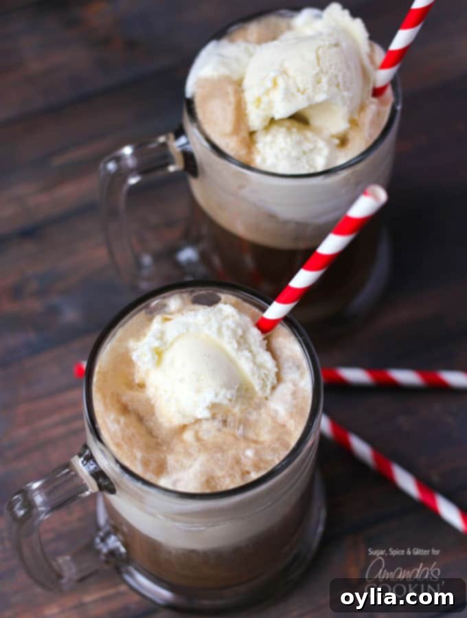 An overhead photo of two root beer float cocktails in clear mugs served with a red and white striped straw.