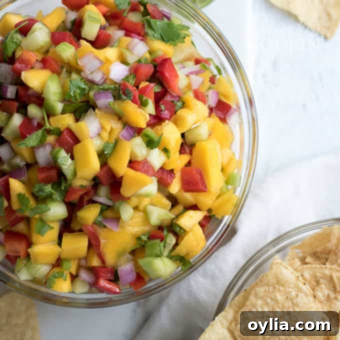 A photo of bright, colorful mango salsa in a clear glass bowl, garnished with fresh cilantro.