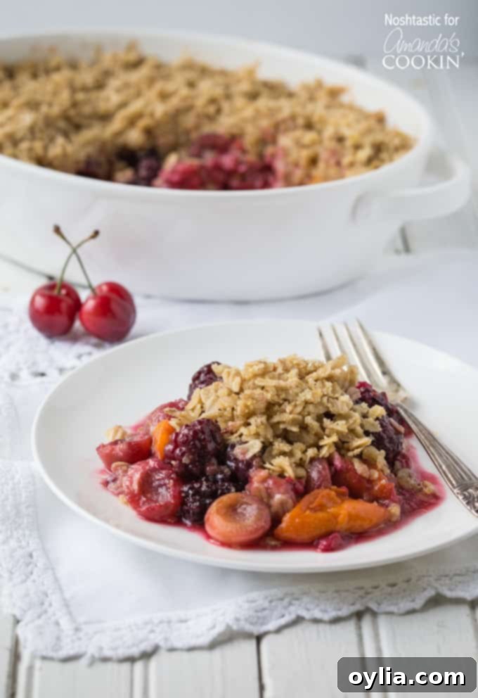 Summer fruit crisp on a white plate with a fork on the side.
