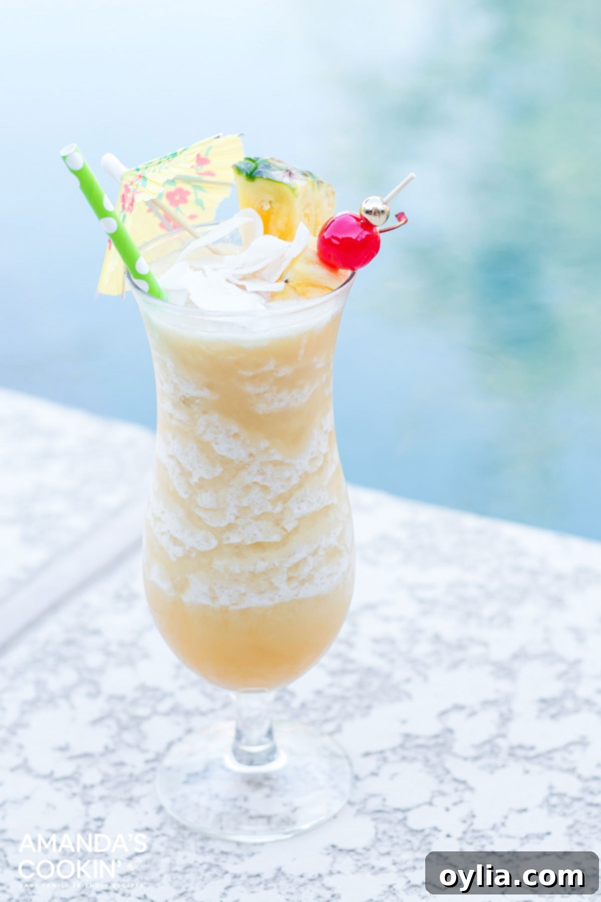 A frosty Pina Colada drink sitting by a pool, garnished with pineapple and a cherry, evoking a tropical summer vibe.
