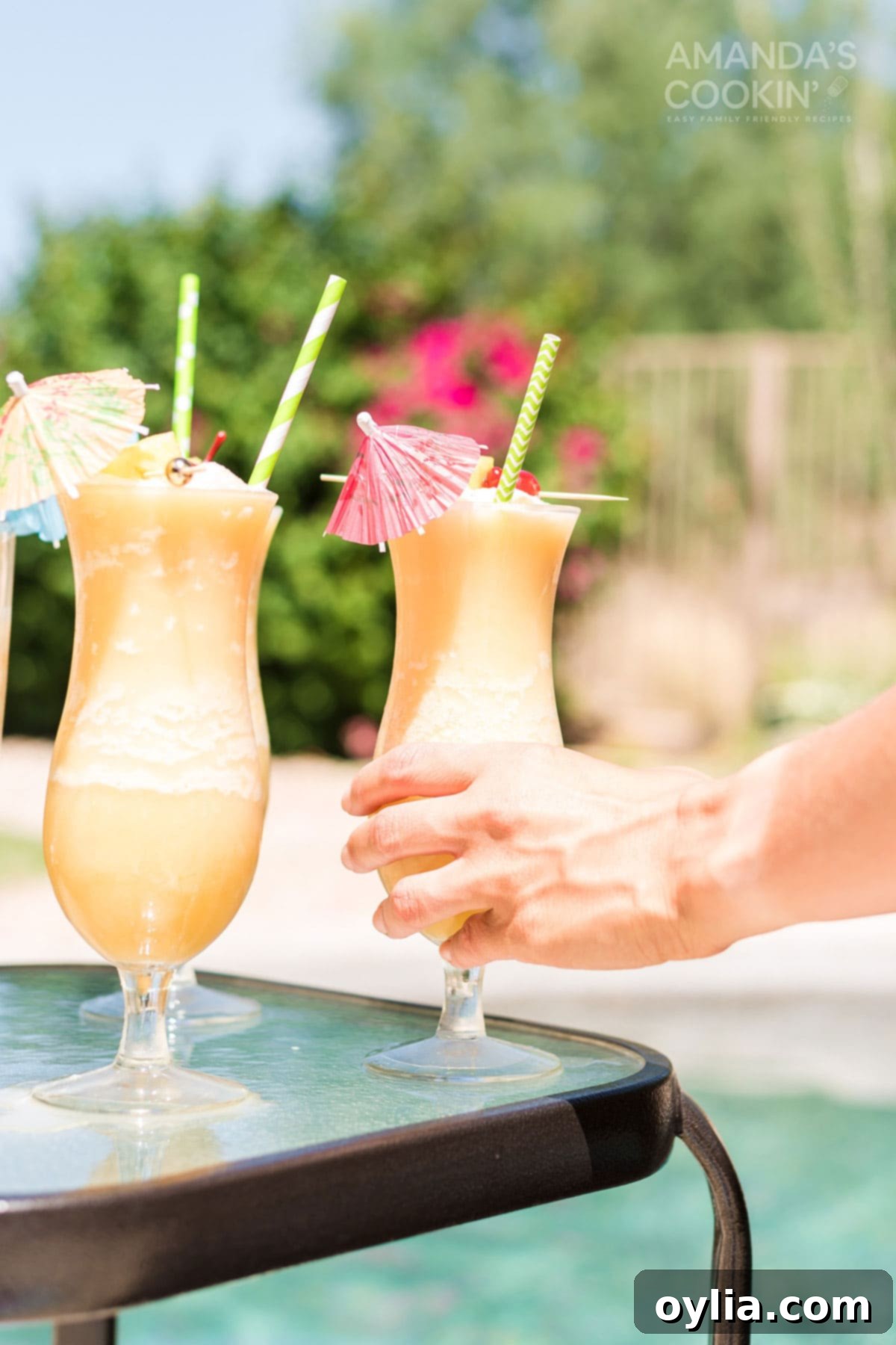 Hand reaching for a frosty Pina Colada cocktail by the pool, emphasizing enjoyment and relaxation.