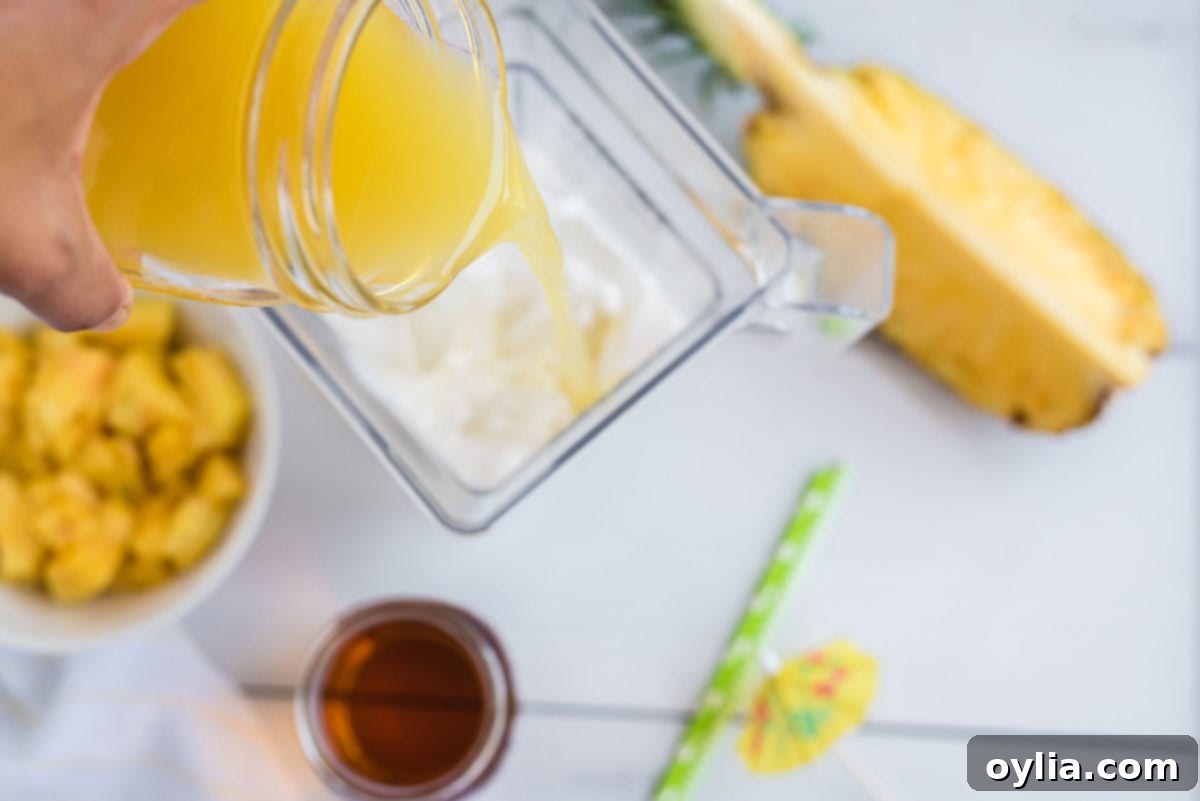 Adding pineapple juice to a blender with other Pina Colada ingredients.