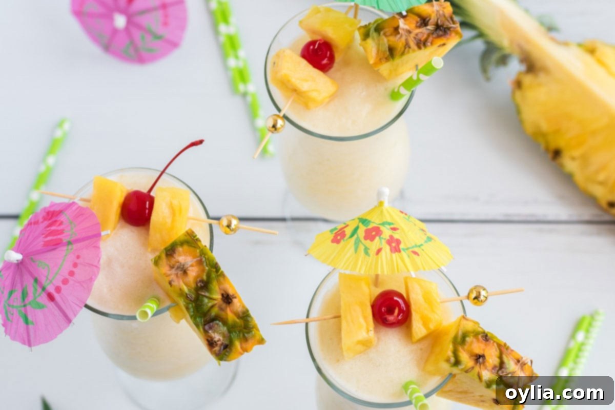 Three beautifully garnished Pina Coladas with cherry and pineapple wedges, ready to serve.