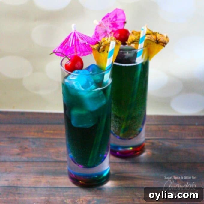 Two vibrant Blue Mermaid Cocktails in tall glasses, garnished with cherries and pineapple, ready for summer enjoyment.