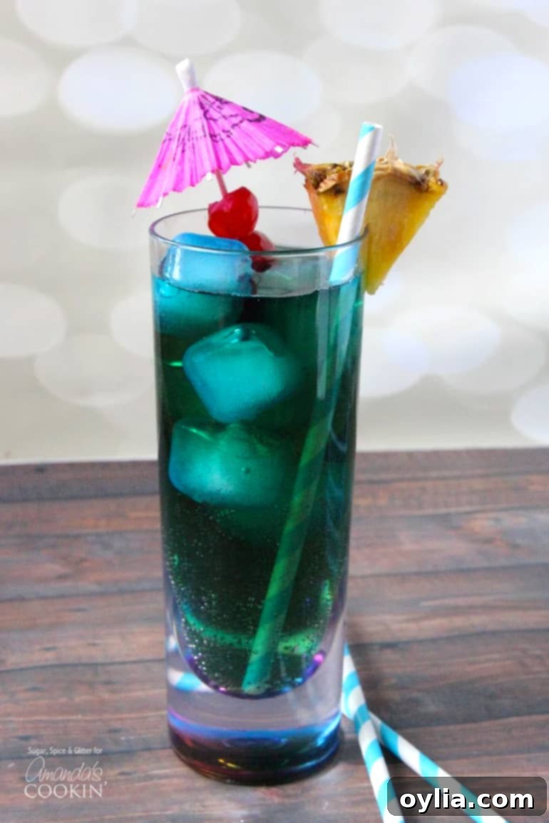 A beautifully presented Blue Mermaid Cocktail in a tall glass, adorned with a miniature parasol, evoking a festive, tropical vibe.