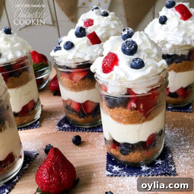 A close up of no bake berry cheesecake trifles in mason jars on a wooden cutting board.