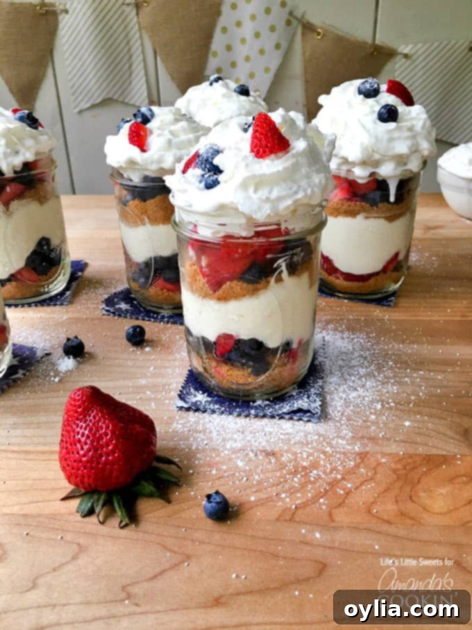 A close up of no bake berry cheesecake trifles in mason jars on a wooden cutting board.