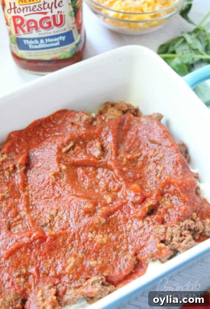 An overhead photo of a generous pour of Ragu Homestyle sauce covering the ground beef, pepperoni, ricotta, and noodles in the dish.