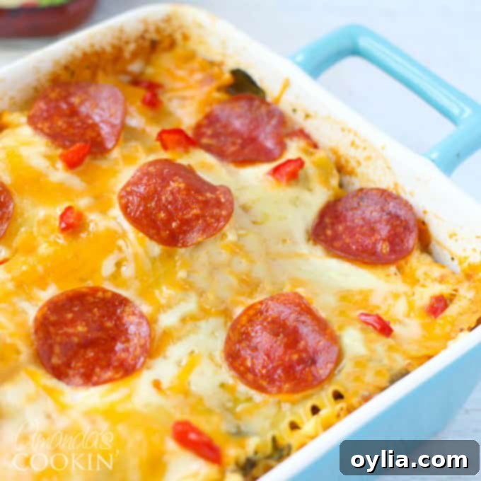 A close up photo of the baked pizza lasagna in a blue casserole dish, with a perfectly melted and golden-brown cheesy top.