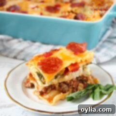 A close up of pizza lasagna on a white and gold plate.