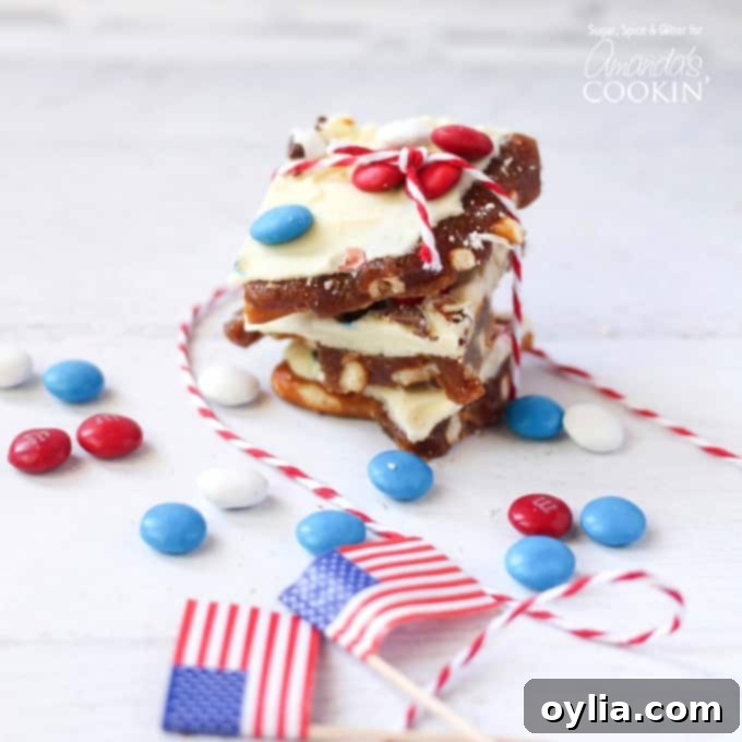Patriotic candy bark stacked on top of each other with American flags and red, white and blue M&Ms scattered in the background.