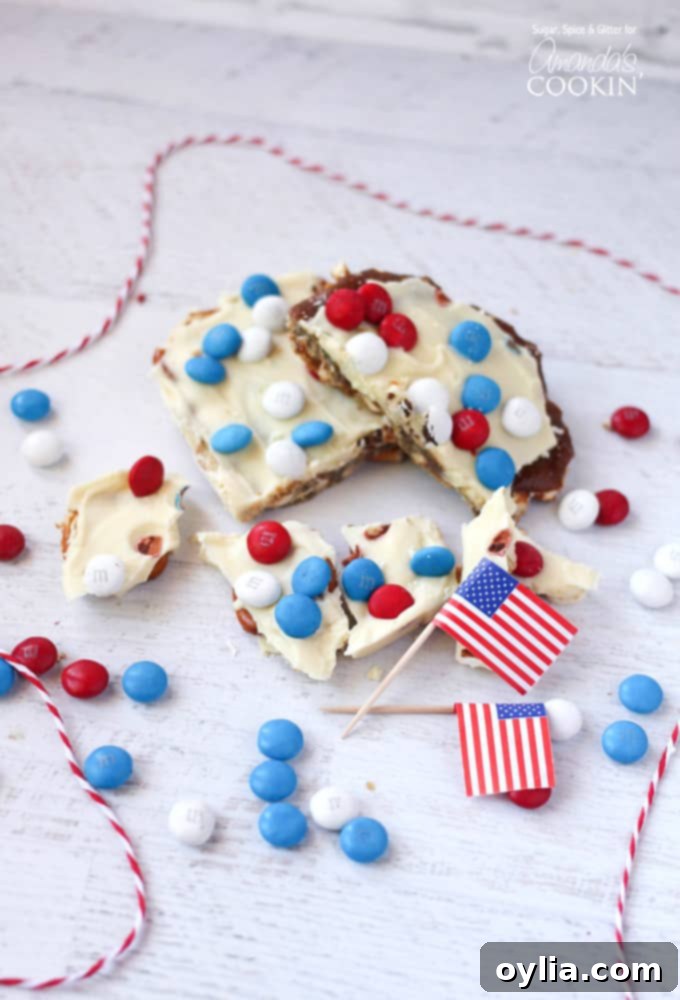 An overhead photo of patriotic candy bark with red white and blue M&Ms and American flags in the background.