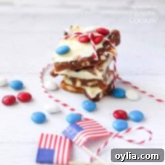 4th of July M&M bark stacked on top of each other with American flags and red, white and blue M&Ms scattered in the background.