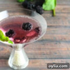 Midnight Blackberry Martini 6 A close up of a blackberry gin martini topped with fresh blackberries and mint leaves.