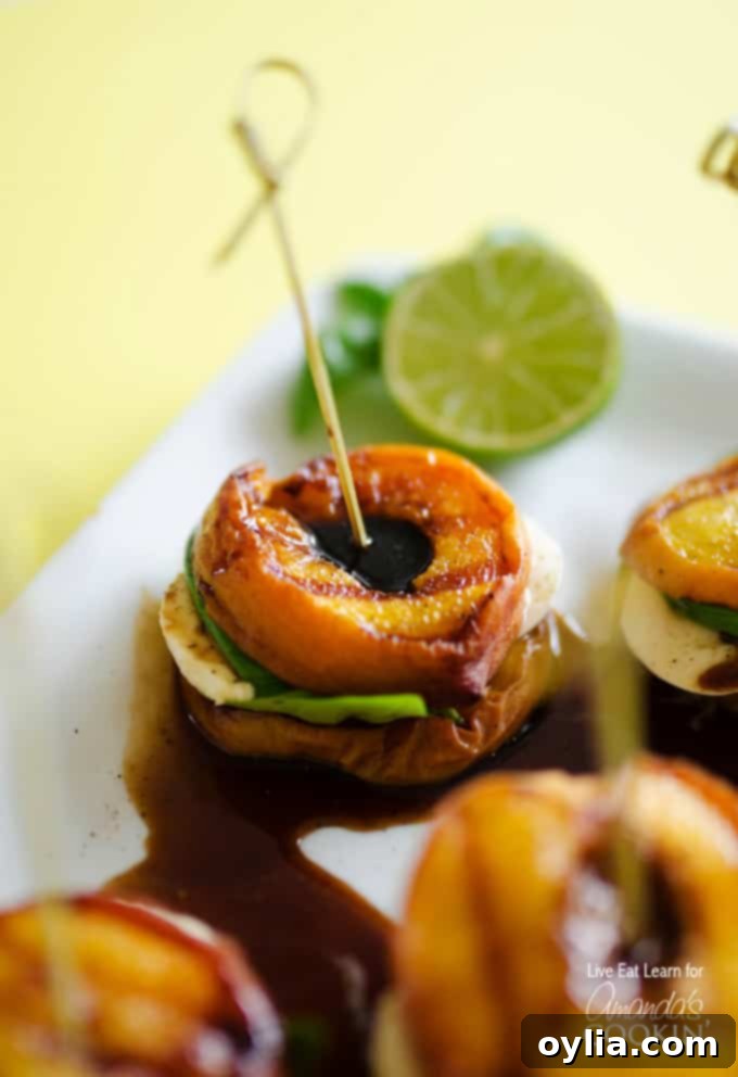 A close up of grilled peach caprese on a white platter with a lime wheel in the background.