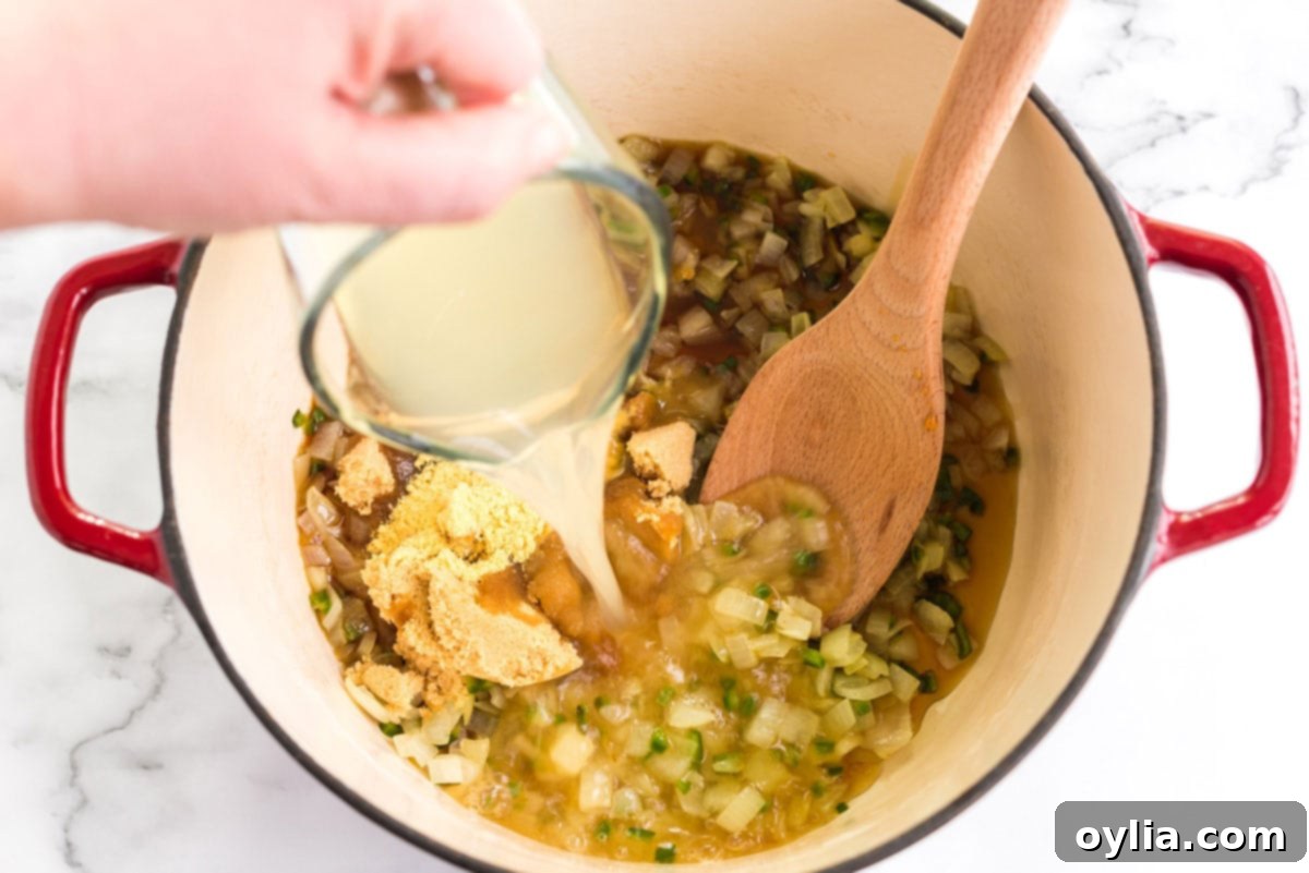 Perfectly Homemade Baked Beans 7 A Dutch oven containing brown sugar, maple syrup, liquid smoke, dry mustard, and bean liquid, ready for stirring.