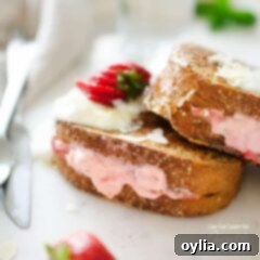 A close up of a strawberry cream french toast on a plate, garnished with powdered sugar
