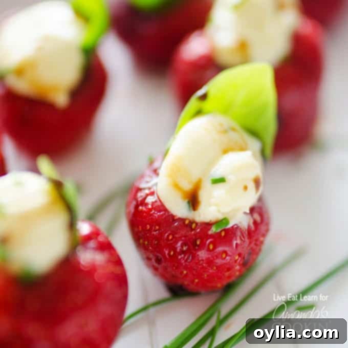 A close up photo of strawberries filled with whipped brie and topped with a basil leaf.